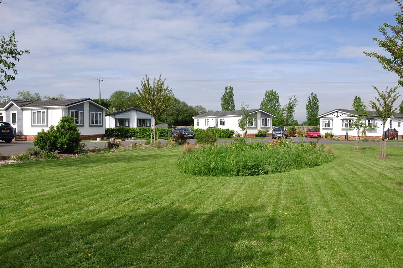 Lush green perfectly mown lawn with homes in the distance